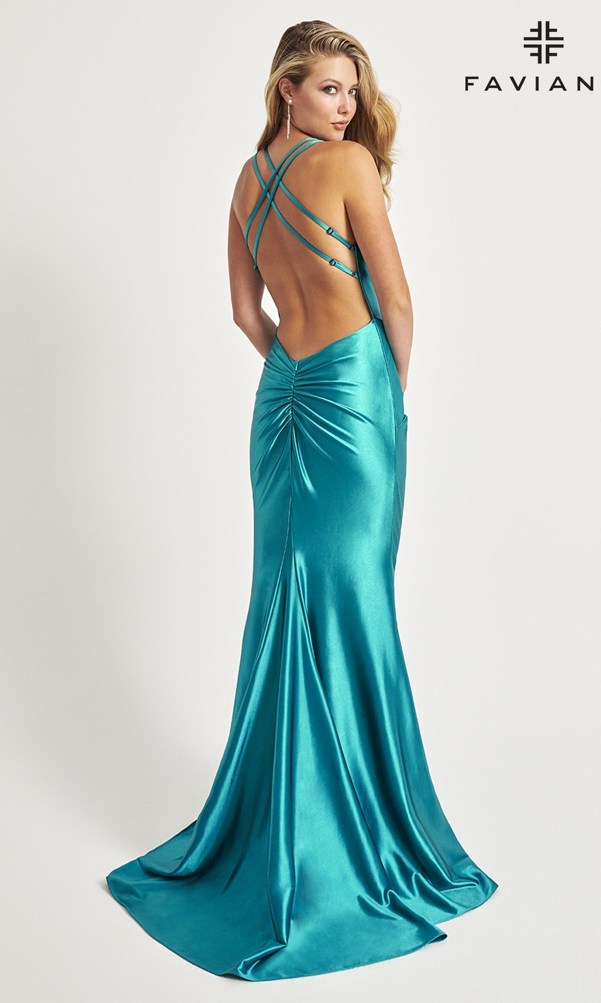 A woman models the Faviana Twist-Front Long Formal Dress 11024 in teal stretch satin, featuring a ruched back and crisscross straps, posing against a plain white background with the Faviana logo in the corner.